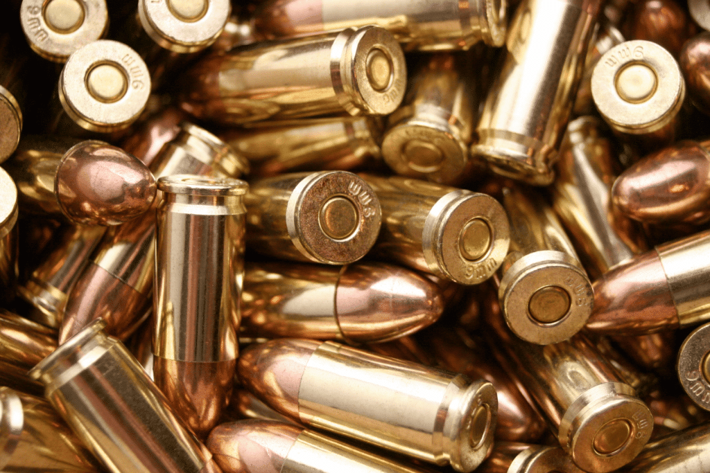 A close-up view of a pile of shiny brass and copper bullets, showing their metallic casings and rounded tips.