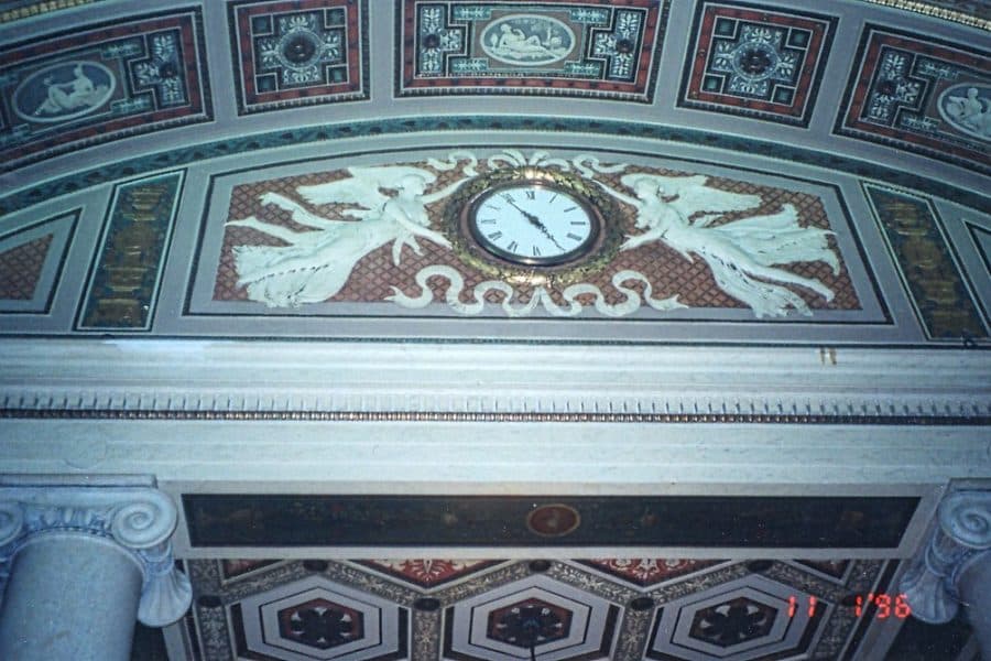 2A Marketplace: Private Firearm Classifieds A decorative clock set in an ornate wall with white sculpted figures on either side, surrounded by intricate patterns and classical artwork on the ceiling of a grand building. Private sale of guns.