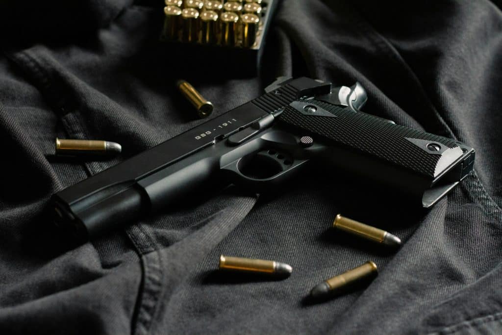 2A Marketplace: Private Firearm Classifieds A black handgun lies on dark fabric, surrounded by loose bullets and a box of ammunition in the background. Private sale of guns.